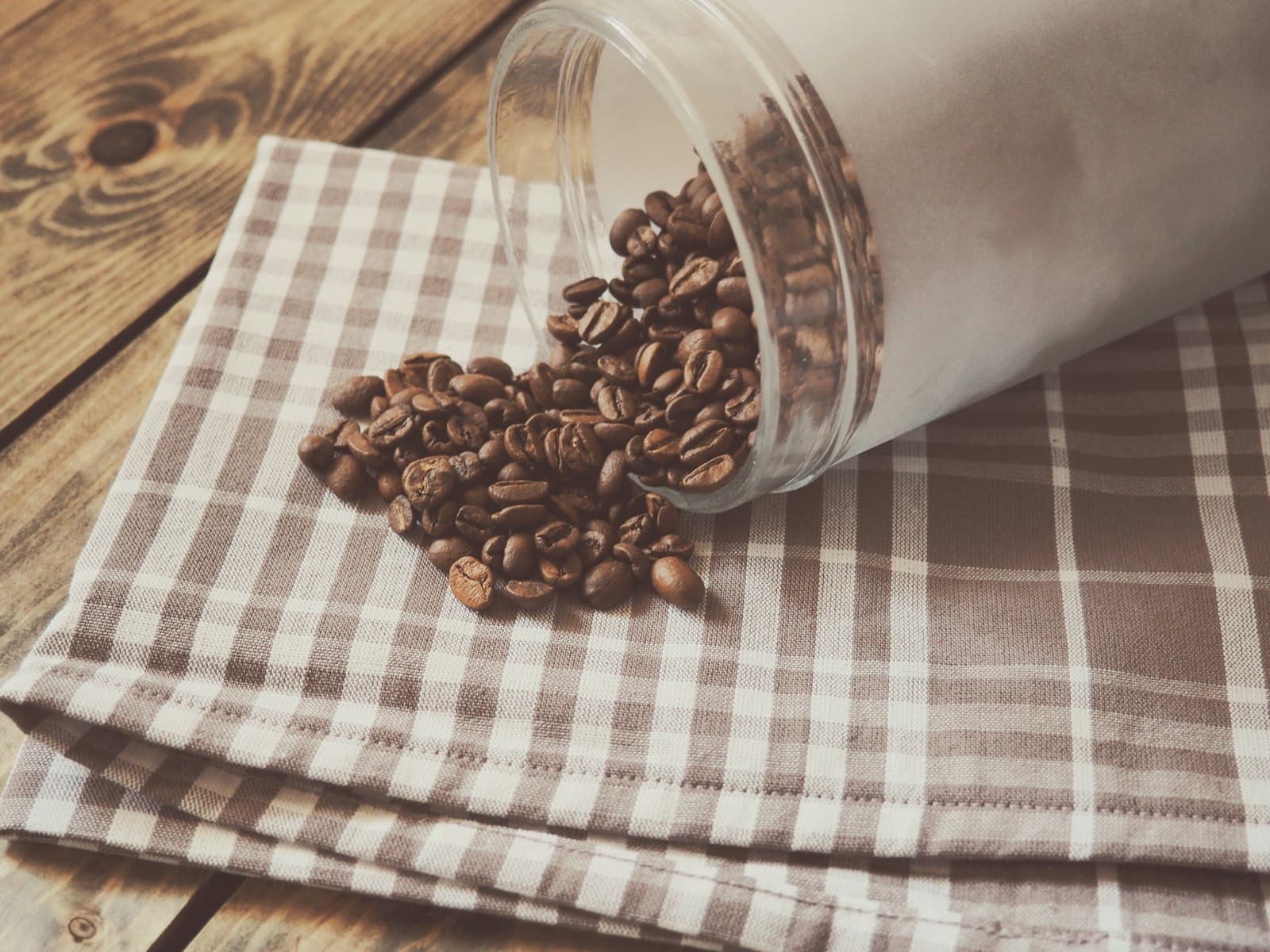 A glass storage jar filled with roasted coffee beans