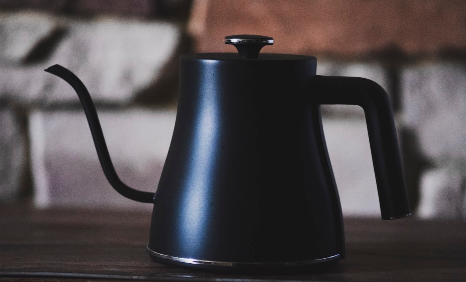 A black gooseneck kettle on a wooden table