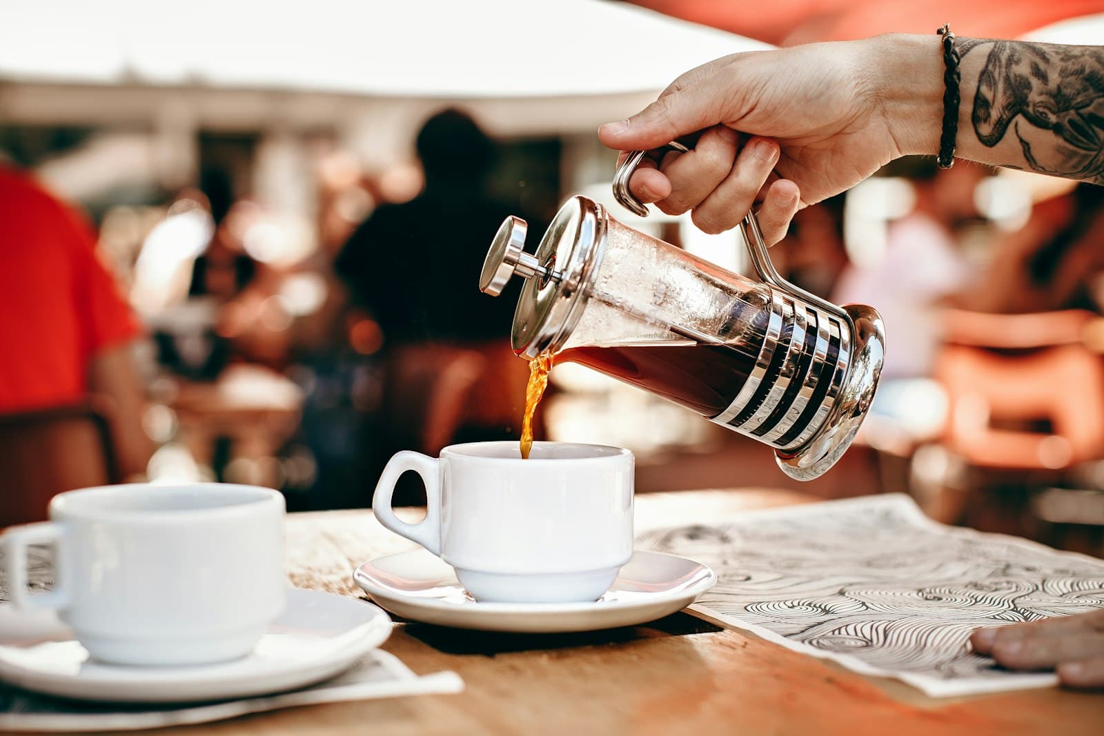 Coffee being poured from a French press into a white cup