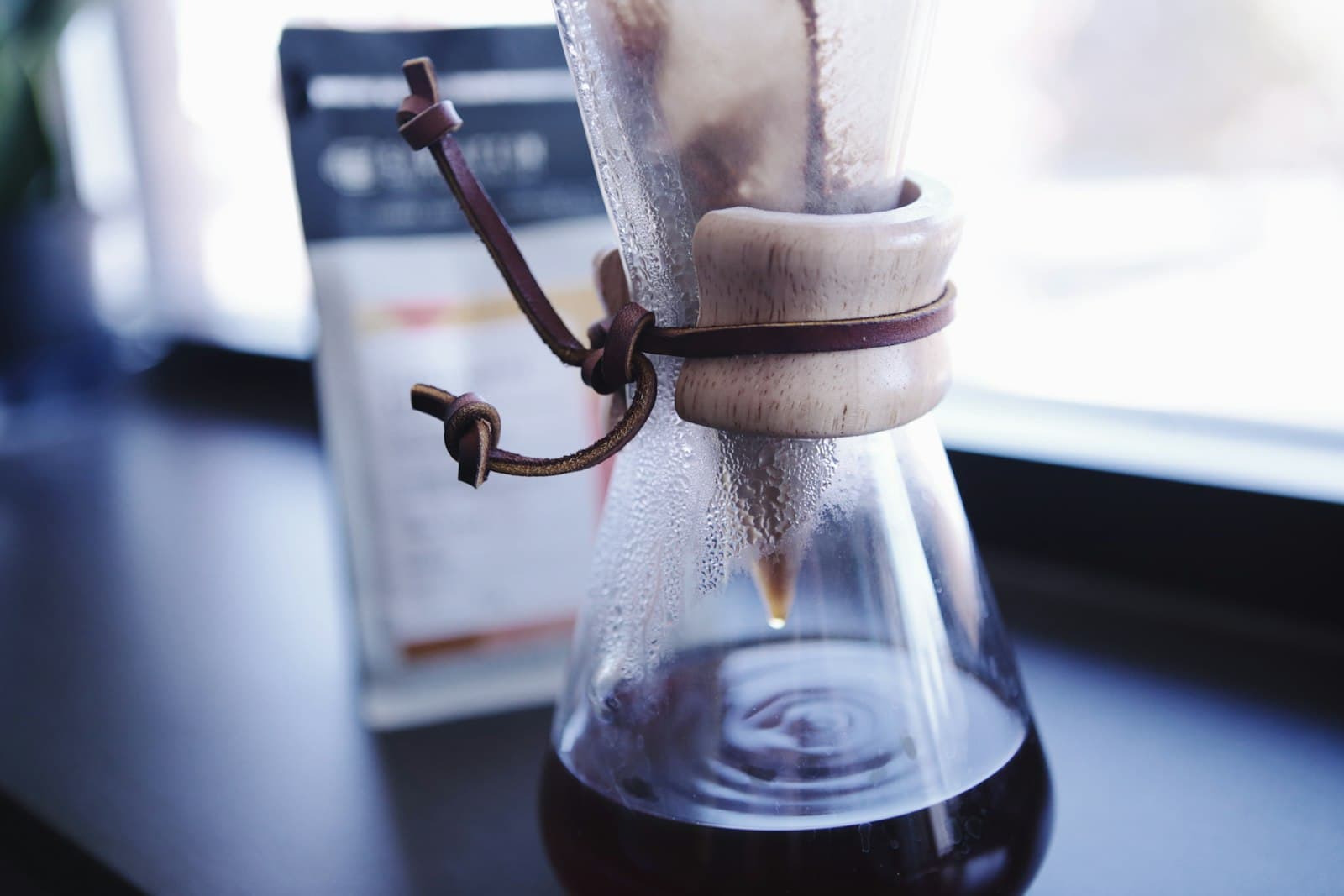 A glass pour-over carafe with a paper filter mid-brew