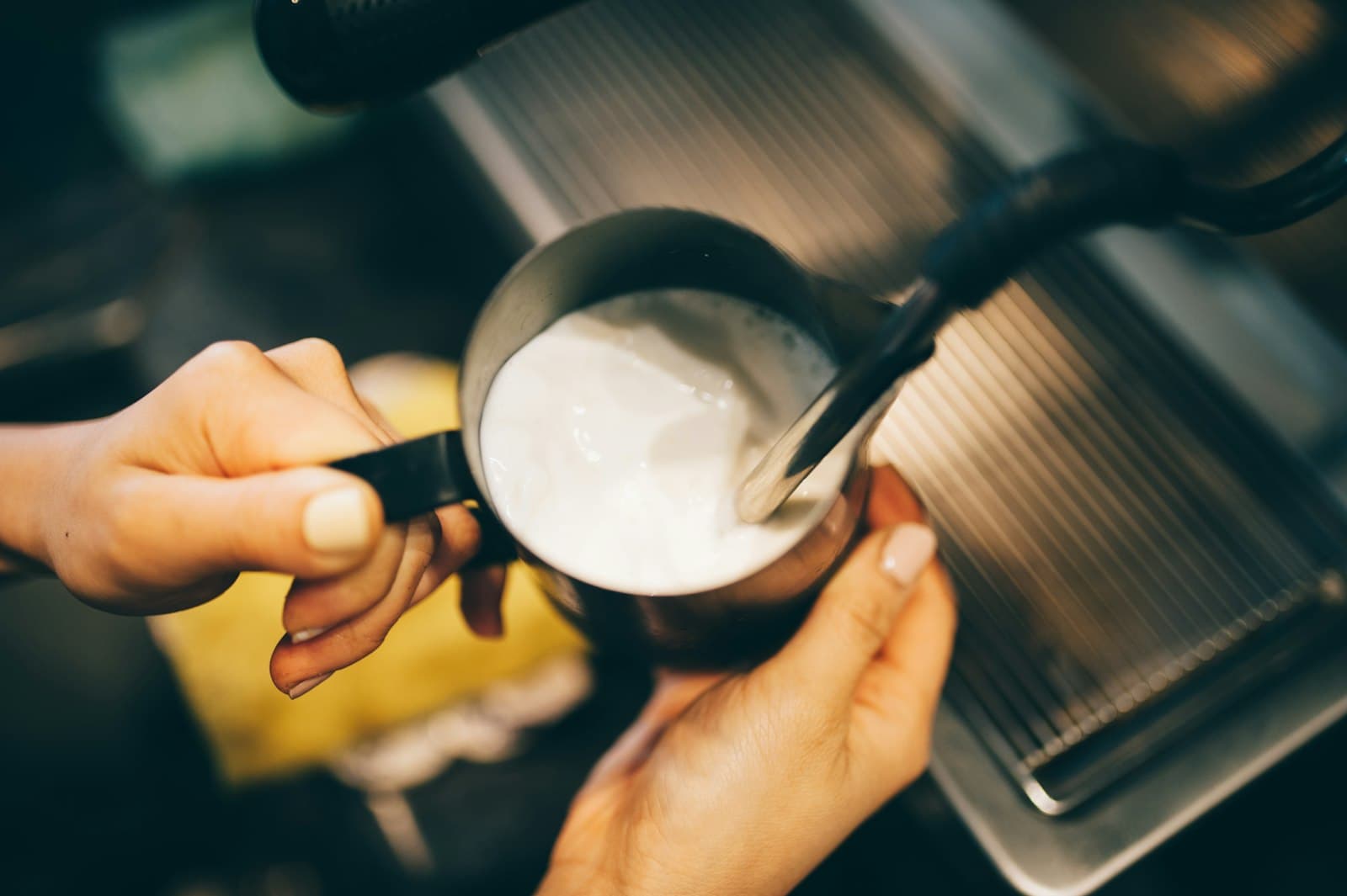 Hands holding a slim handheld milk frothing wand