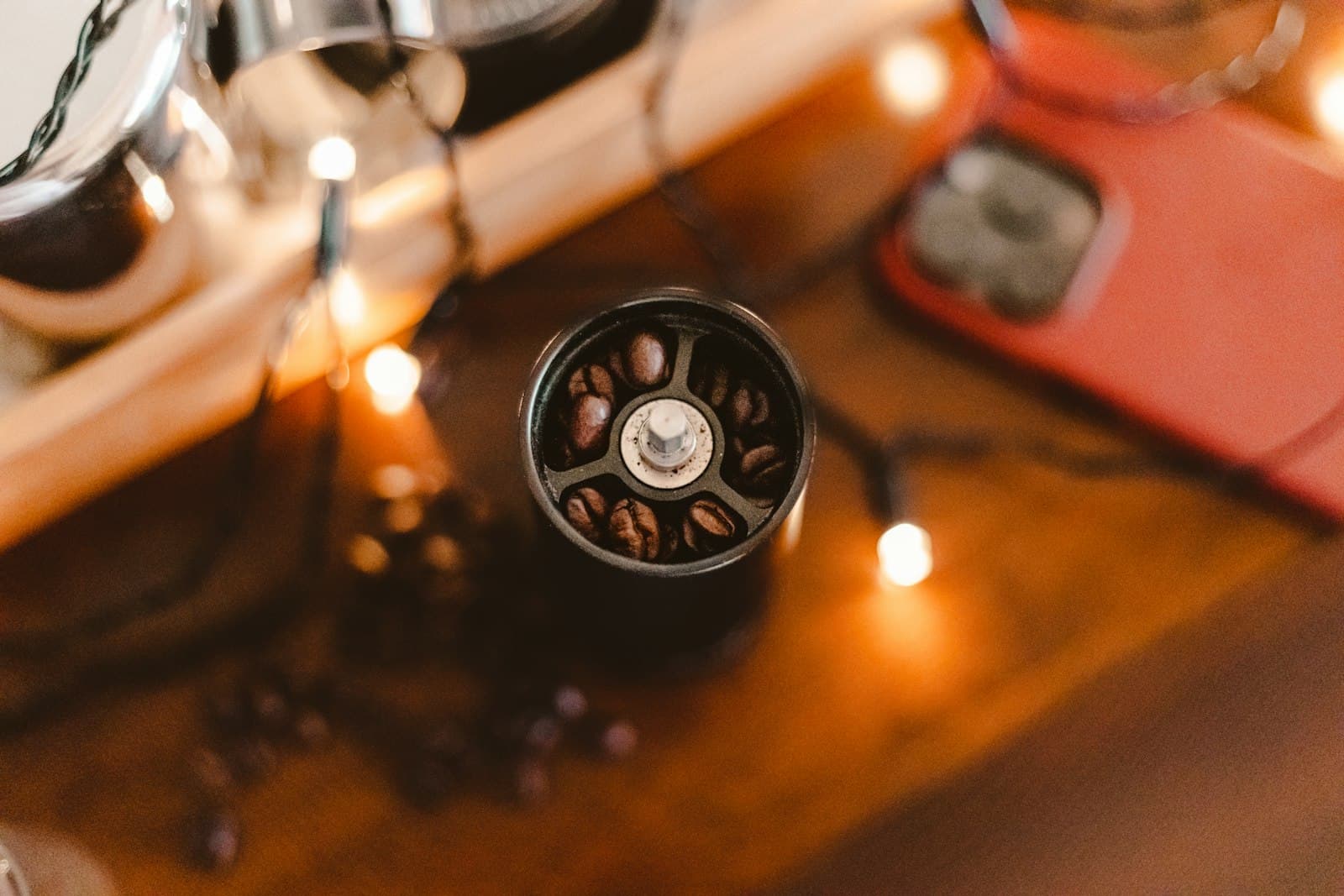 A compact hand coffee grinder sitting on a wooden table